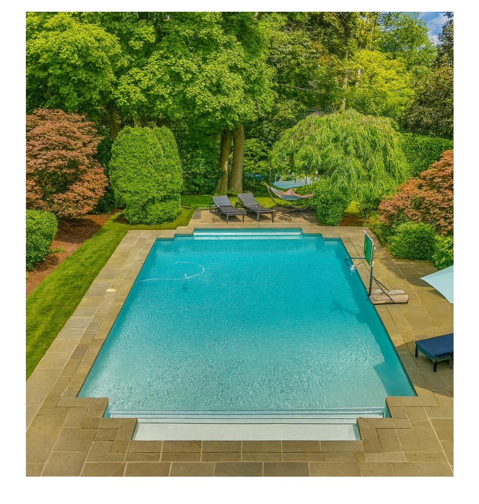 Heated in-ground pool with bluestone surround and mature landscaping at 44 Adams Drive.